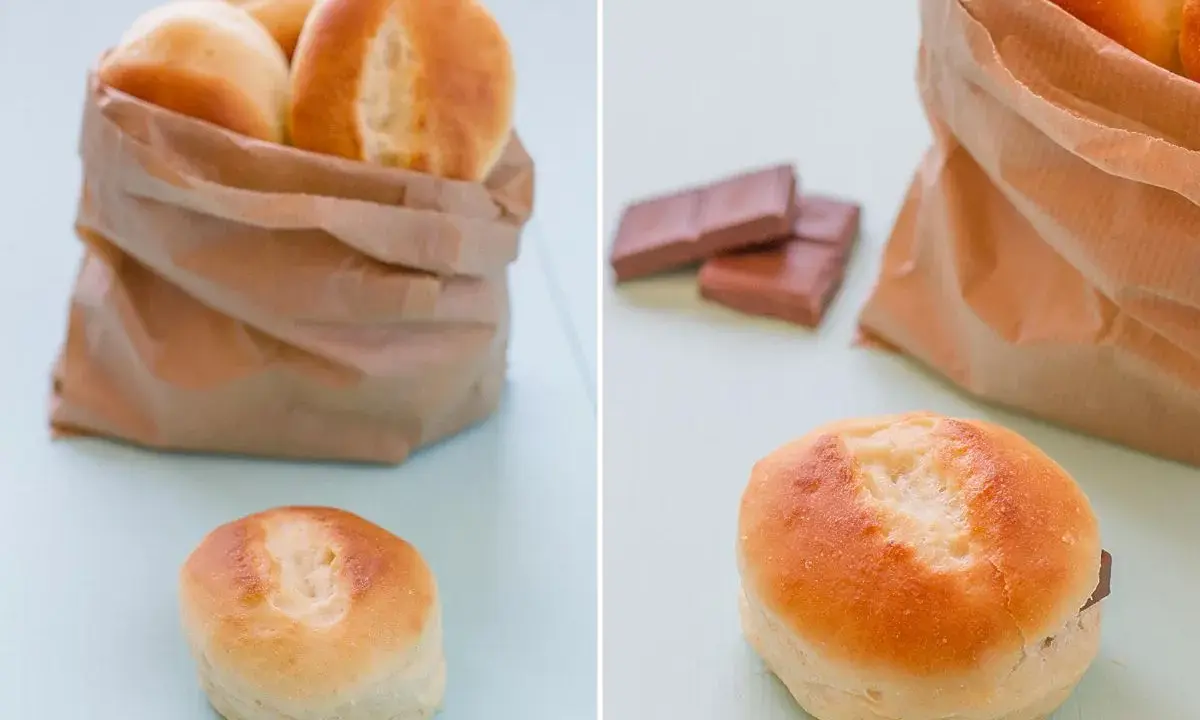 Pan de leche recién horneado en una bolsa de papel, con uno abierto mostrando chocolate.
