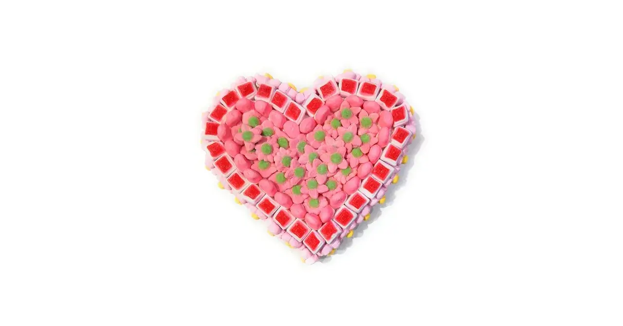 Corazón de tartas de chuches de San Valentín, decorado con flores rosas y detalles verdes.