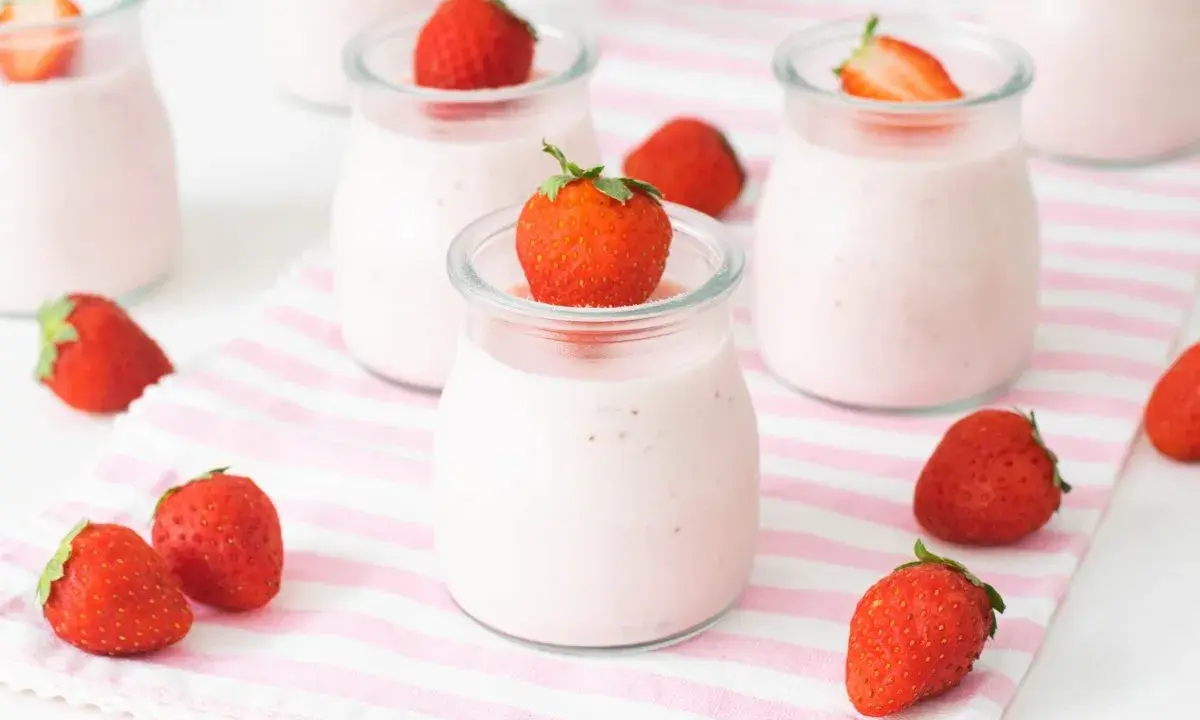 Deliciosos petit yogures de fresa en vasitos de cristal, decorados con fresas frescas.