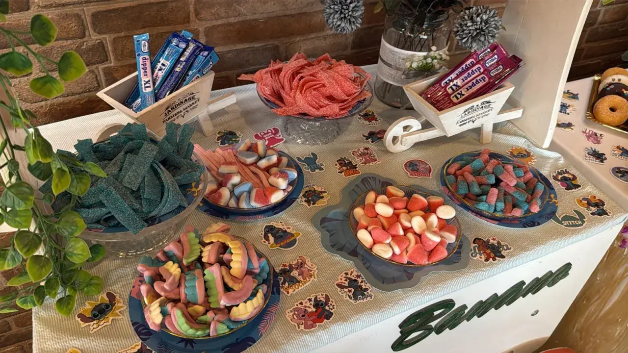 Una mesa llena de todas las chuches del mundo: gominolas azules, rojas, rosas y de muchos colores, dispuestas en cuencos y carretillas.