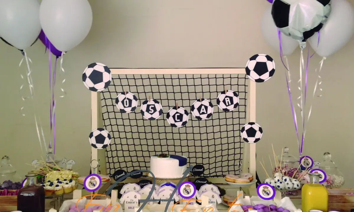Mesa de chuches del Real Madrid: balones de fútbol, globos, tarta y dulces para una fiesta temática.