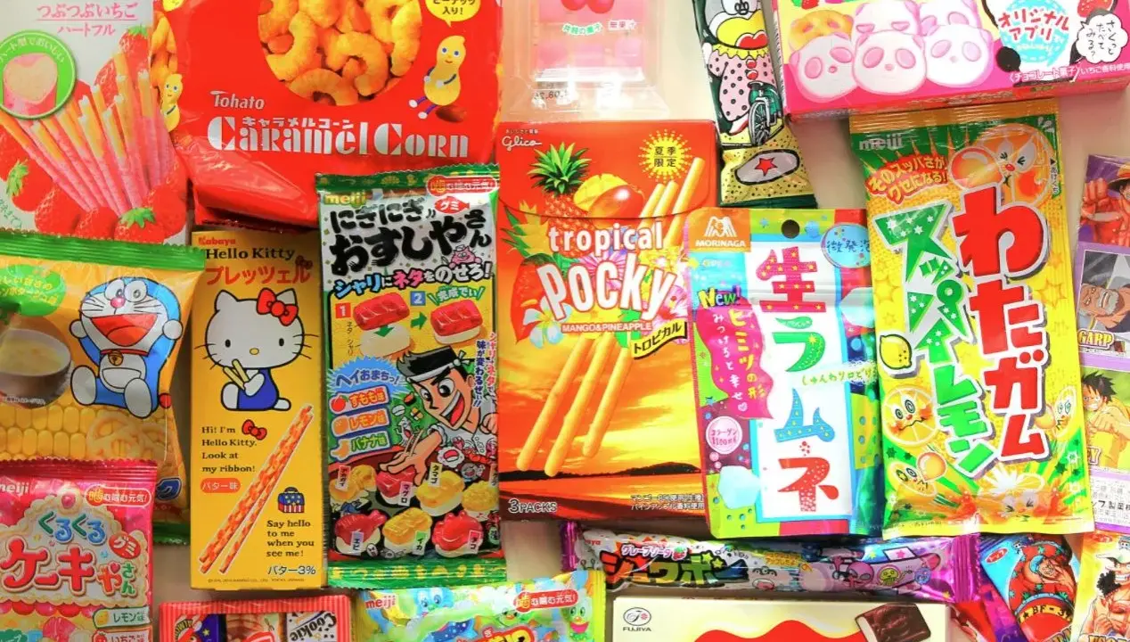 Un surtido vibrante de chuches famosas japonesas, incluyendo Pocky, Caramel Corn y dulces de Hello Kitty y Doraemon.