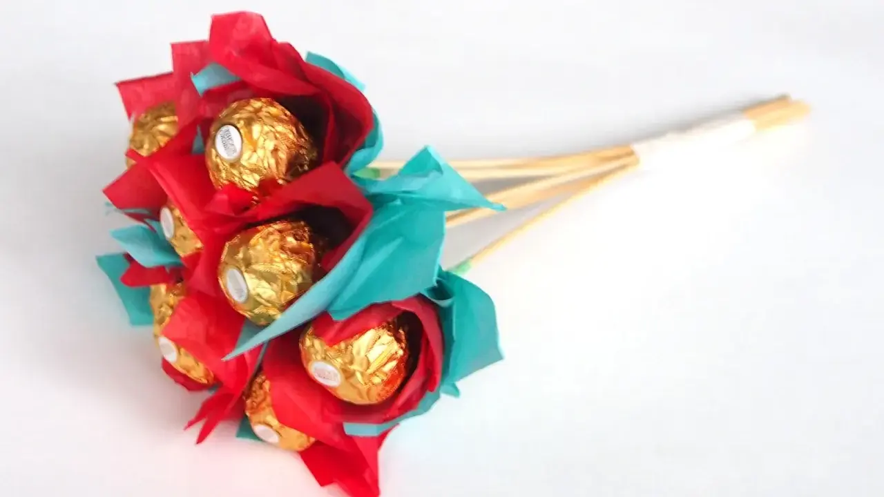 Un ramo de bombones dorados envueltos en papel rojo y turquesa, ideal para un regalo dulce y original.