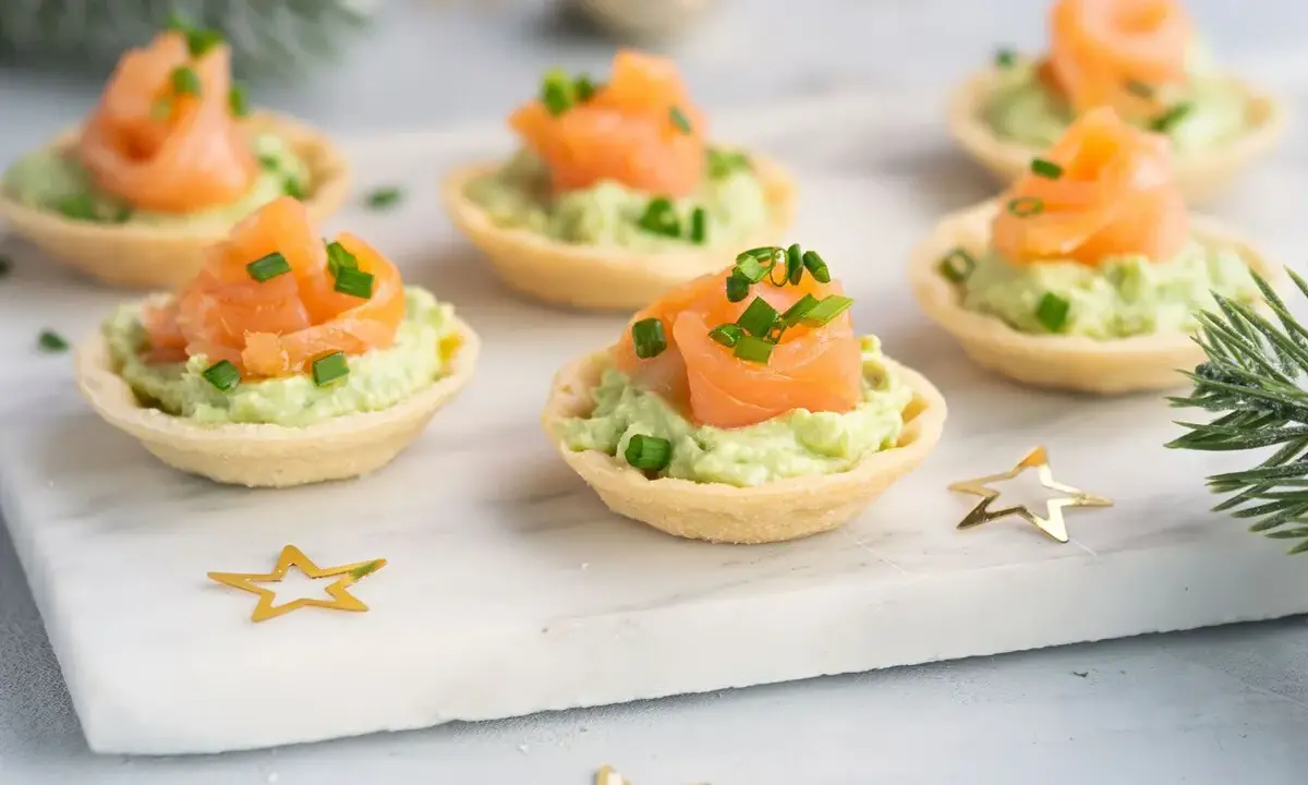 Aperitivos baratos para mucha gente: canapés de salmón y aguacate, decorados con cebollino y estrellas doradas.