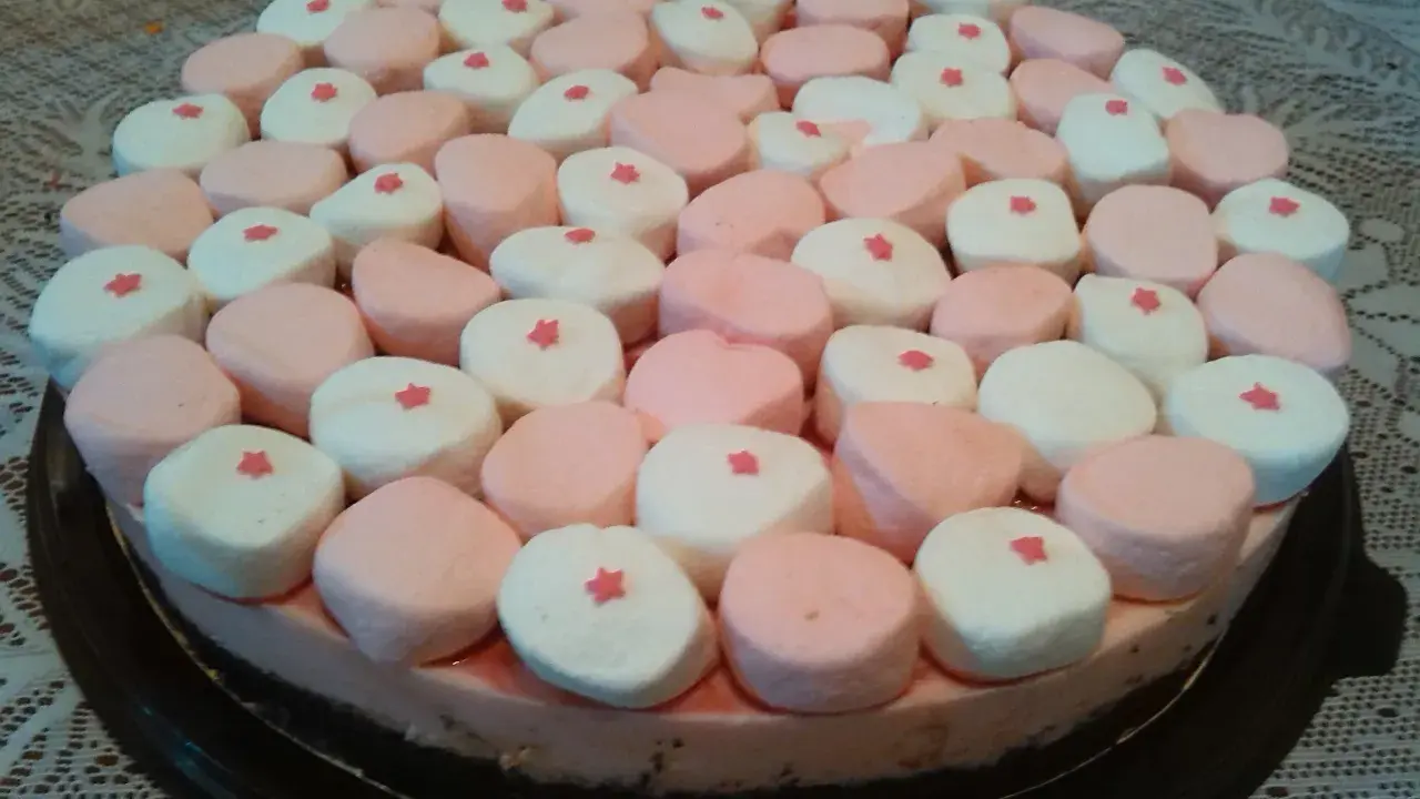 Tarta de nubes de golosina, cubierta con malvaviscos rosas y blancos, cada uno con una pequeña estrella roja.