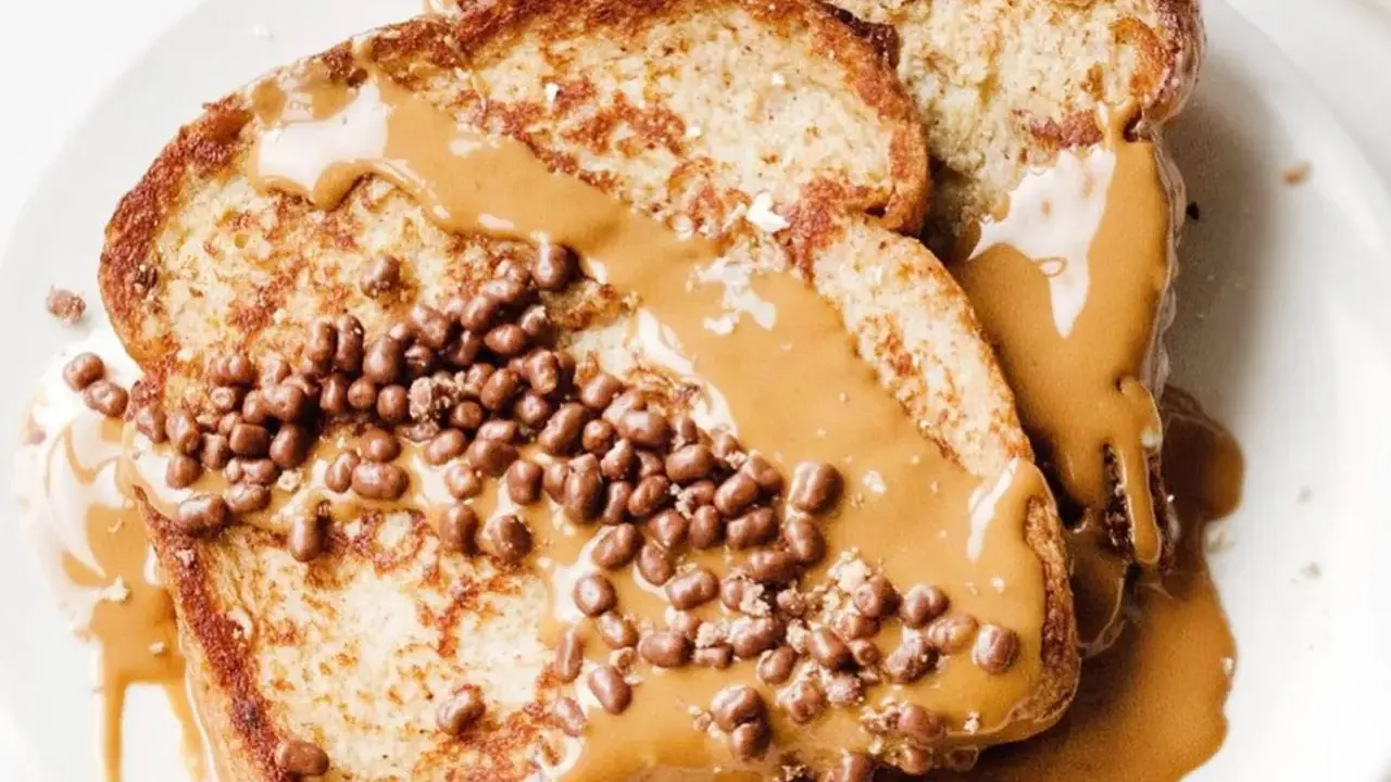 Tostadas francesas cubiertas con crema de cacahuete y crujientes bolitas de chocolate. Un desayuno delicioso y tentador.