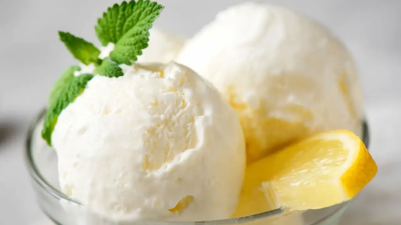Delicioso helado de limón casero en copa de cristal, adornado con menta fresca y rodajas de limón.