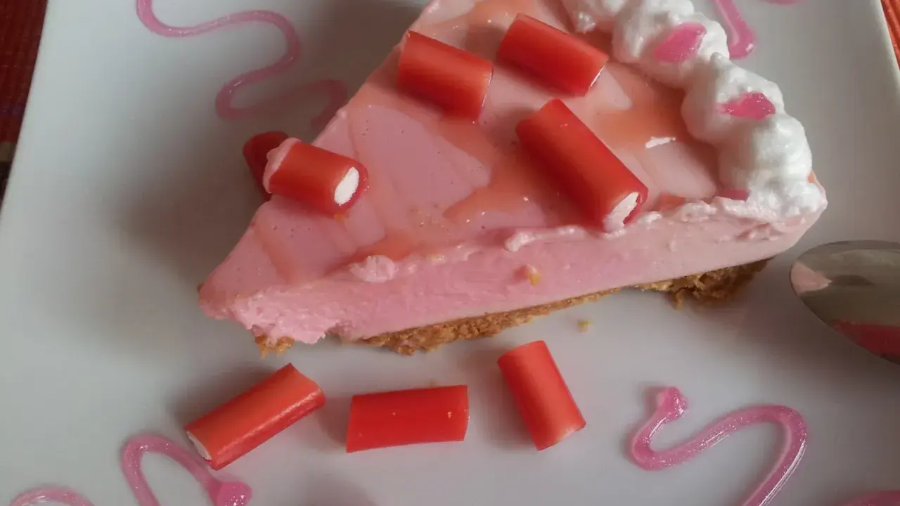 Deliciosa tarta de regaliz rojo con crema rosa y adornos de regaliz.