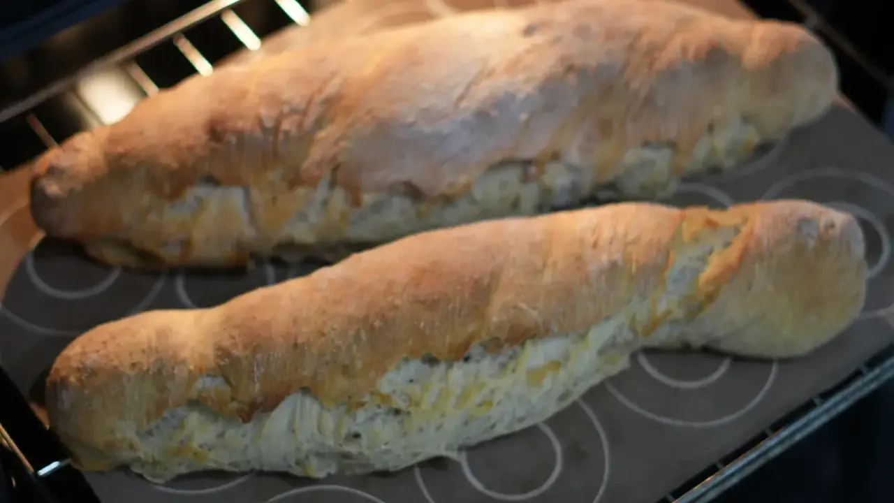 Dos panes dorados recién horneados, hechos con la ayuda de la Thermomix, reposan sobre una bandeja en el horno.