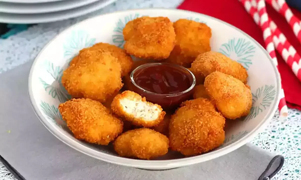 Un plato lleno de crujientes nuggets caseros, listos para mojar en salsa barbacoa.