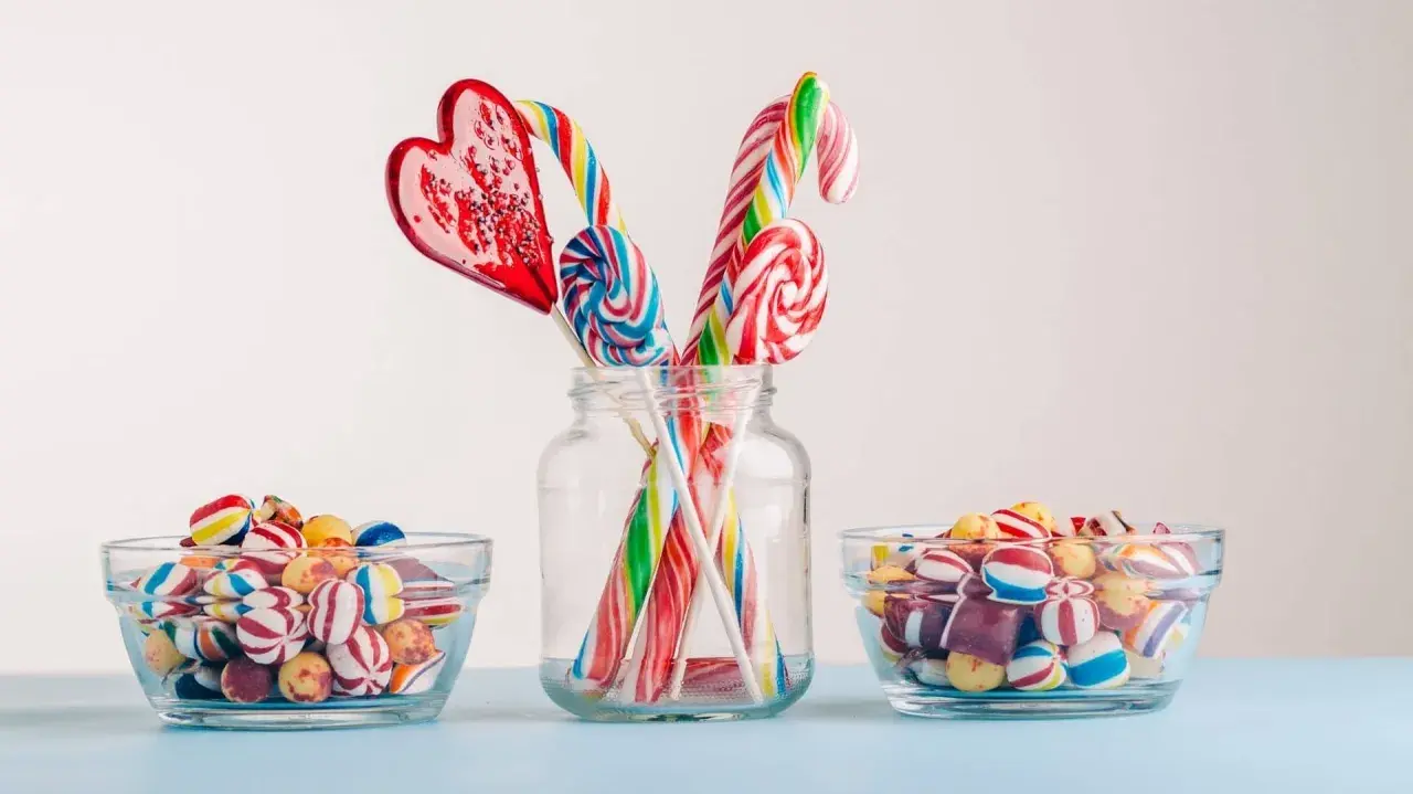 Dulces coloridos y piruletas en forma de corazón y espiral, perfectos para manualidades como regalar chuches.