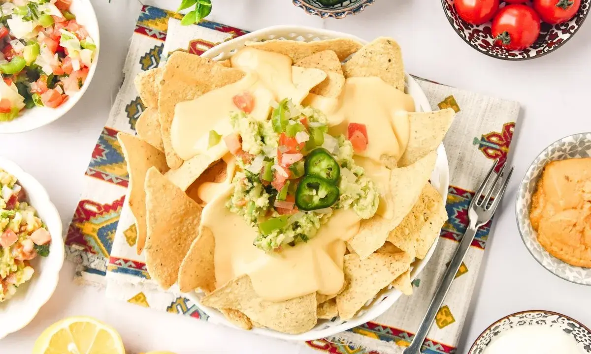 Nachos con queso cubiertos de guacamole y pico de gallo, listos para disfrutar.