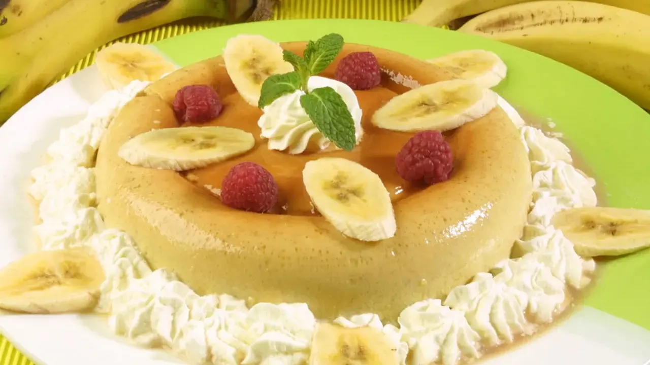 Delicioso flan de plátano adornado con rodajas de plátano, frambuesas y crema batida. Un postre perfecto para cualquier ocasión.