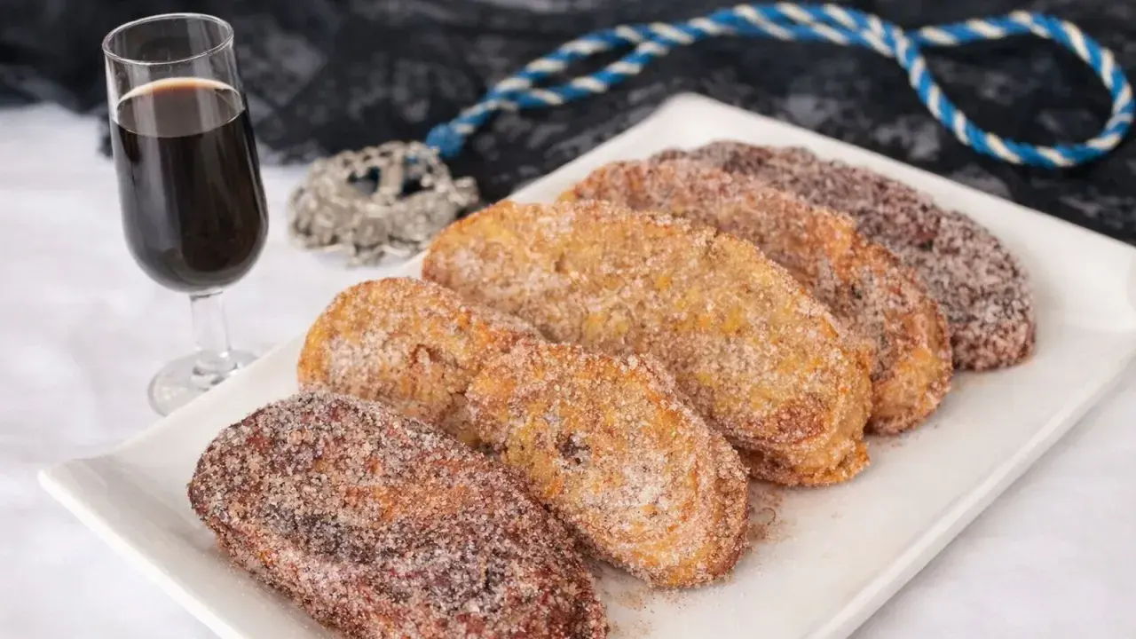 Torrijas cubiertas de azúcar y canela, listas para disfrutar. Un delicioso pan para torrijas, acompañado de una copa de vino dulce.