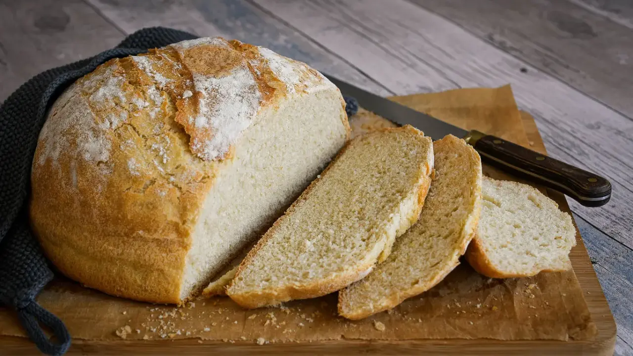 Un delicioso pan casero con levadura fresca, recién horneado y cortado en rebanadas sobre una tabla de madera.