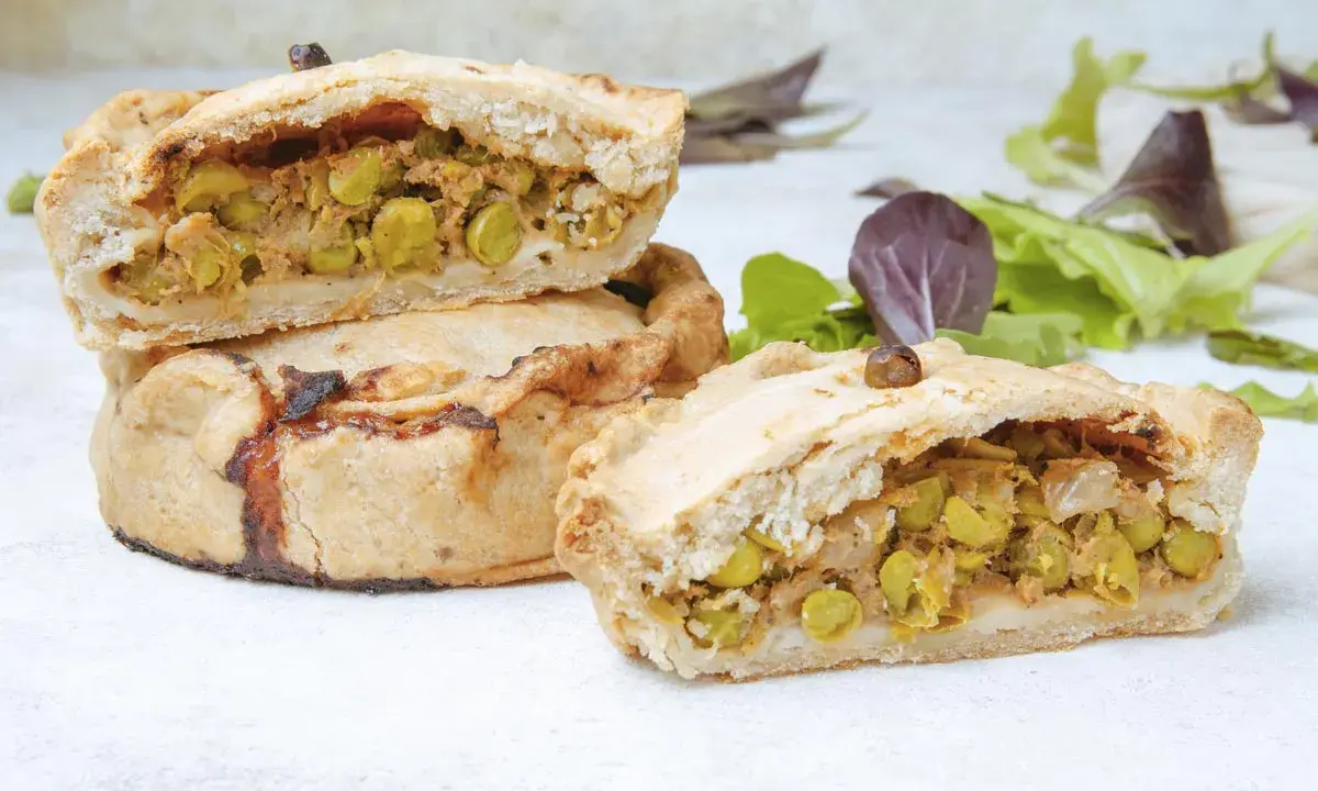 Empanadas mallorquinas rellenas de guisantes y carne, con una masa dorada y crujiente.