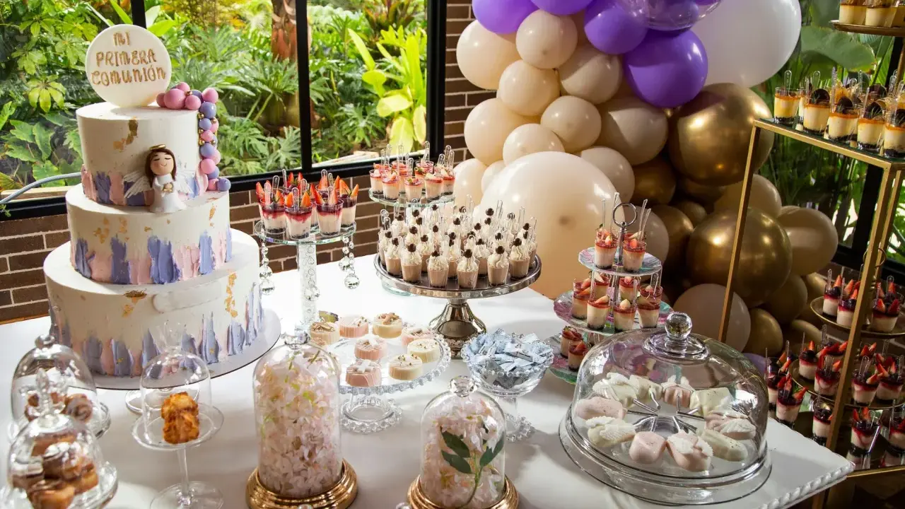 Mesa dulce para comunión con pastel, postres individuales, dulces y globos.