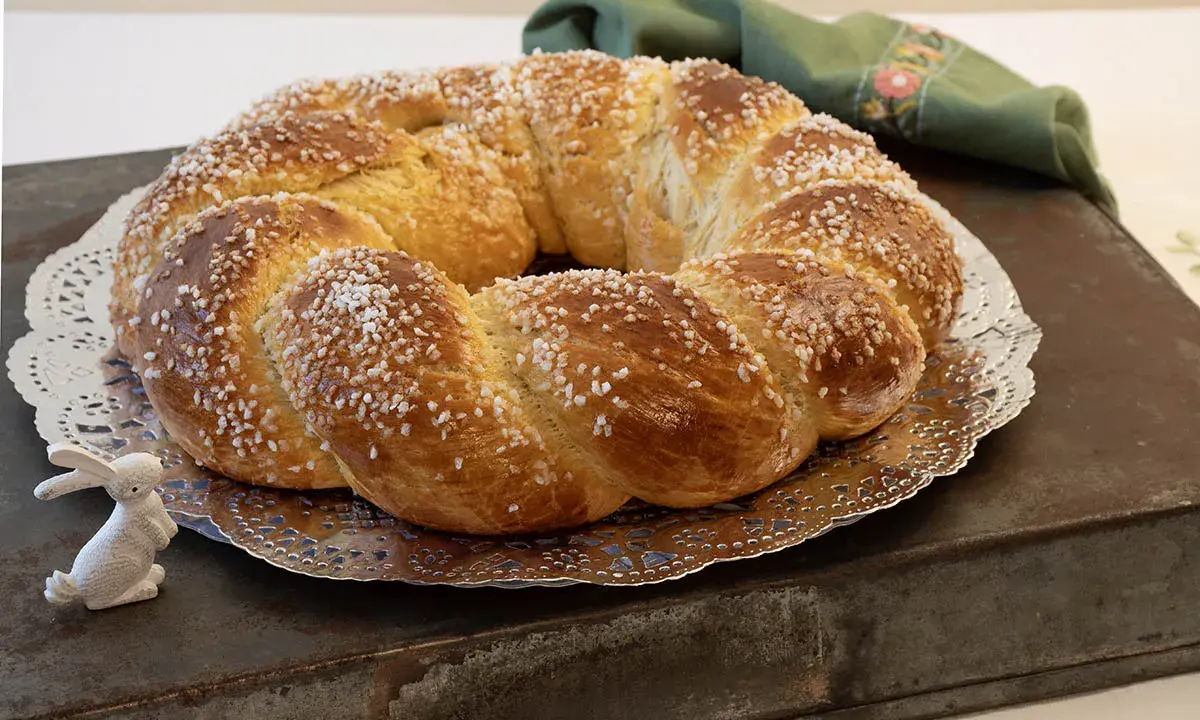 Rosca de Pascua gallega, trenzada y espolvoreada con azúcar, junto a un conejito blanco.