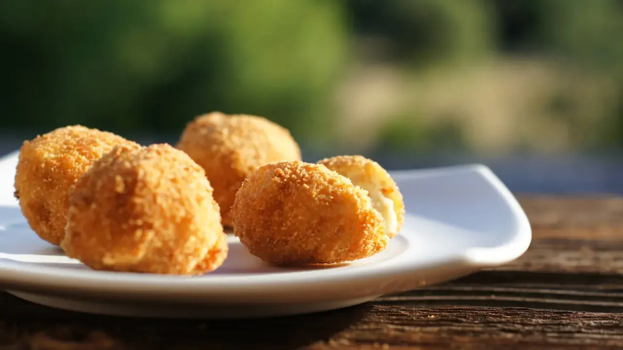 Croquetas caseras doradas y crujientes en un plato blanco, listas para disfrutar.