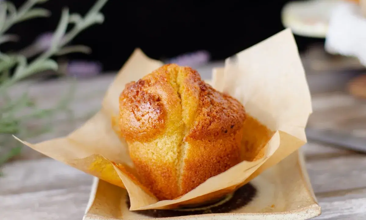 Un muffin dorado, recién horneado, envuelto en papel de horno. Perfecto para acompañar tu proceso de hacer masa madre.