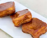 Tres torrijas de miel, doradas y brillantes, reposan en un plato blanco.
