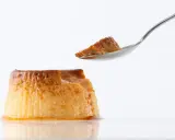 Un trozo de flan casero sin horno en una cuchara, con el resto del postre caramelizado al lado.