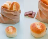 Pan de leche recién horneado en una bolsa de papel, con uno abierto mostrando chocolate.