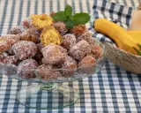 Un tazón lleno de buñuelos de calabaza cubiertos de azúcar, con una ramita de menta encima. Al fondo, calabazas en una cesta.