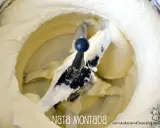 Batidora con pala mezclando nata montada, creando una textura esponjosa y cremosa, lista para postres.