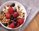 Un tazón de yogur con granola casera, frambuesas y arándanos. Un desayuno saludable y delicioso.