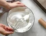 Manos batiendo claras a punto de nieve para un merengue suizo perfecto.