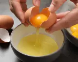 Manos separando la yema de la clara de un huevo. Ideas para saber qué hacer con claras de huevo y yemas.