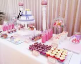 Mesa dulce para 50 cumpleaños con pastel de dos pisos, cupcakes, cake pops, bebidas rosas y palomitas.