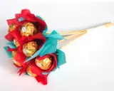 Un ramo de bombones dorados envueltos en papel rojo y turquesa, ideal para un regalo dulce y original.