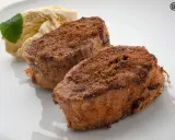 Dos torrijas de chocolate espolvoreadas con cacao y azúcar, acompañadas de helado de vainilla y una hoja de menta.