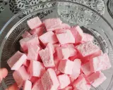 Nubes de golosina rosas cortadas en cubos en un bol de cristal, perfectas para recetas dulces.