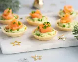 Aperitivos baratos para mucha gente: canapés de salmón y aguacate, decorados con cebollino y estrellas doradas.