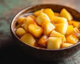 Tazón de macedonia de frutas con trozos de manzana y melocotón glaseados, listos para disfrutar.