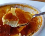 Cuchara levanta un trozo de cremoso creme brulee con su crujiente capa de caramelo tostado.