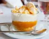 Postre en vaso con capas de galleta, crema y mermelada de mango, coronado con merengue crujiente, como un polvito canario.