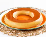 Un delicioso flan de café, con su caramelo dorado, reposa en un plato blanco con borde azul, sobre una esterilla tejida.