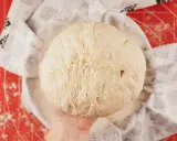 Masa de pan de patata esponjosa, lista para hornear, cubierta con un paño decorado.