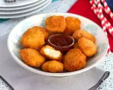Un plato lleno de crujientes nuggets caseros, listos para mojar en salsa barbacoa.
