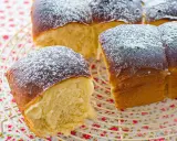 Pan brioche esponjoso y dorado, espolvoreado con azúcar glas sobre una rejilla.