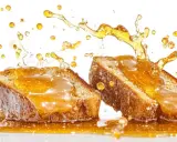 Dos rebanadas de pan cubiertas de miel dorada, con salpicaduras y gotas cayendo. Una deliciosa torrija caramelizada en acción.