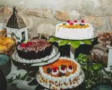 Mesa dulce boda casera con tres pasteles decorados con frutas y chocolate. Hay también cestas con patatas fritas y adornos rústicos.