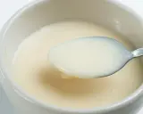 Cuchara con leche evaporada, un ingrediente cremoso y versátil.