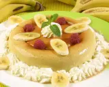 Delicioso flan de plátano adornado con rodajas de plátano, frambuesas y crema batida. Un postre perfecto para cualquier ocasión.