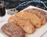 Torrijas cubiertas de azúcar y canela, listas para disfrutar. Un delicioso pan para torrijas, acompañado de una copa de vino dulce.