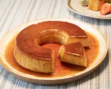 Un delicioso flan de leche condensada con caramelo líquido, servido en un plato de madera.